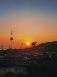 Silhouette boats moored in sea against romantic sky at sunset