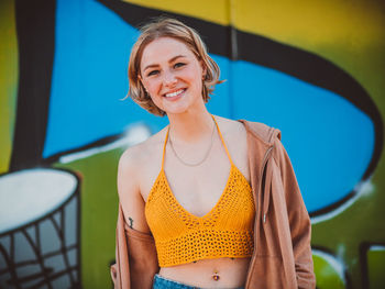 Portrait of smiling young woman standing against blue background