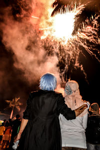 Rear view of people standing against sky at night