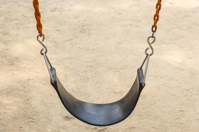 Black seat and red chain of swing in playground