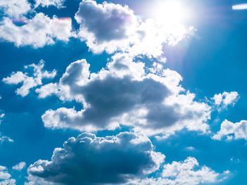 Low angle view of sunlight streaming through clouds