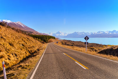 Road amidst mountains against clear blue sky