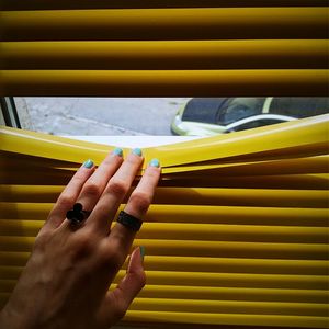 Close-up of hand on yellow car against sky