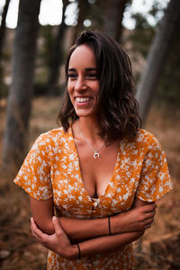 Close-up of smiling young woman looking away standing in forest