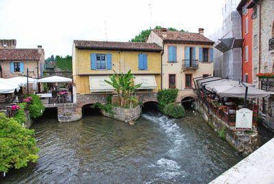 Houses by river and buildings against sky