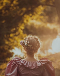 Rear view of woman against trees during sunrise