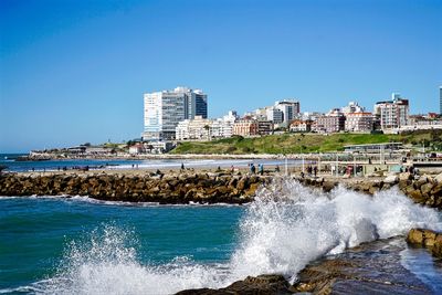 Sea by city against clear blue sky