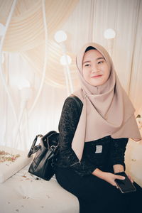 Portrait of smiling young woman standing against wall