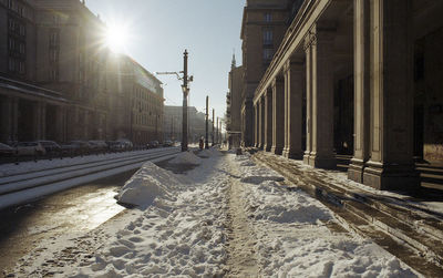 Snow covered street amidst buildings in city