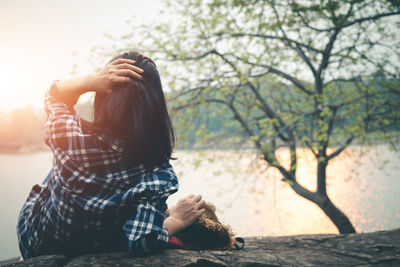 Woman reclining on rock against lake