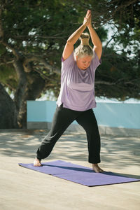 Full length of young woman exercising at beach