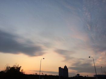 Low angle view of silhouette communications tower against sky during sunset