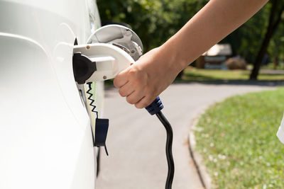 Cropped hand charging car at station