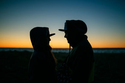 Silhouette people standing on land against sky during sunset