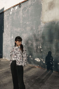 Portrait of woman standing against wall