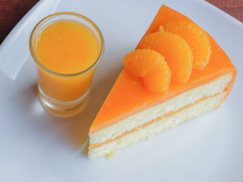 Close-up of cake slice with orange juice on table