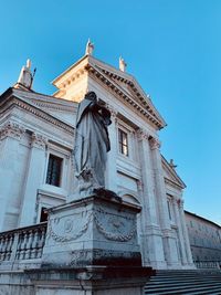 Low angle view of statue of building against blue sky