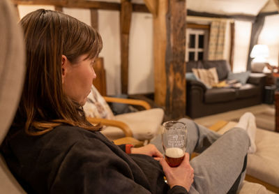 Side view of young woman sitting on bed at home