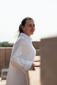 Young woman standing against railing