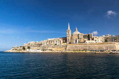 Buildings at waterfront against blue sky