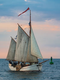 Sailboat sailing in sea against sky during sunset