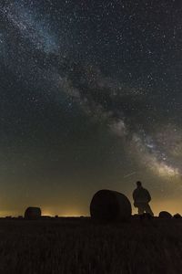 Silhouette man on field against sky at night