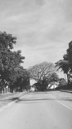 Road by trees against sky