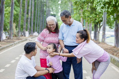 Smiling family standing on road against trees