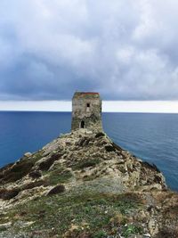 Lighthouse by sea against sky