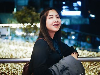 Portrait of young woman standing in balcony at night