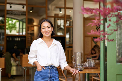 Portrait of young woman standing in cafe