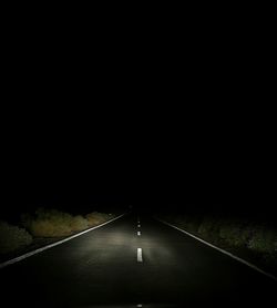 Road amidst trees at night