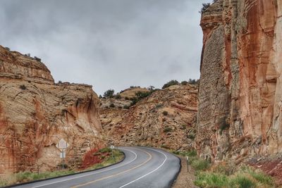 Road leading towards rock formation against sky