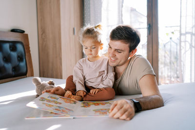 Mother and daughter sitting on bed at home