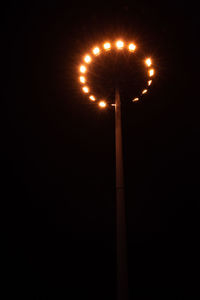 Low angle view of illuminated street lights against sky at night