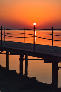 Pier over sea against sky during sunset