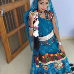 Girl in traditional clothing standing against wall