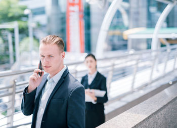Businessman answering smart phone while standing in city