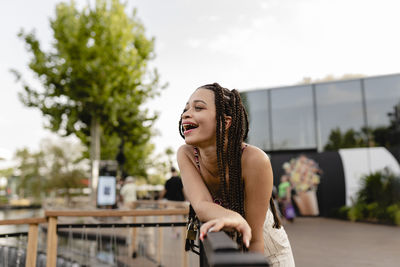 Happy young woman leaning on railing