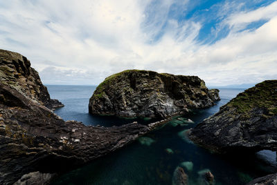 Panoramic view of rocks on sea shore against sky