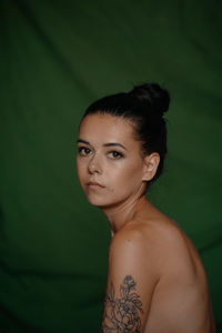 Portrait of shirtless woman against green background