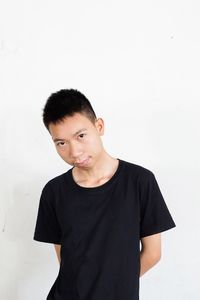 Portrait of young man standing against white background