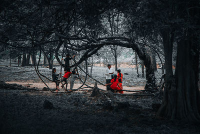 People sitting on land in forest during winter