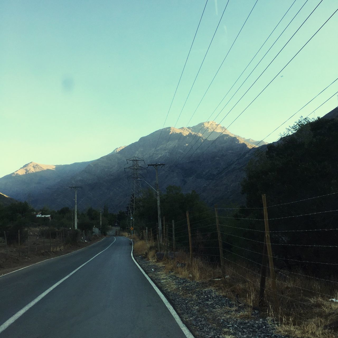 mountain, the way forward, transportation, road, clear sky, landscape, mountain range, sky, tranquil scene, road marking, diminishing perspective, tranquility, country road, scenics, nature, beauty in nature, vanishing point, empty road, power line, blue