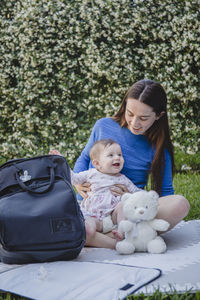 Portrait of young woman and baby sitting on field at park