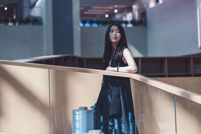 Young woman looking down while standing by railing