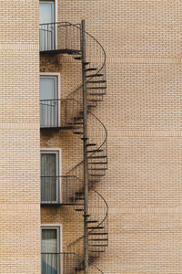 Low angle view of spiral stairs against brick wall