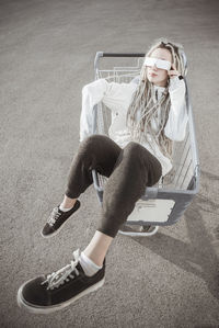 High angle view of young woman with dreadlocks sitting in shopping cart