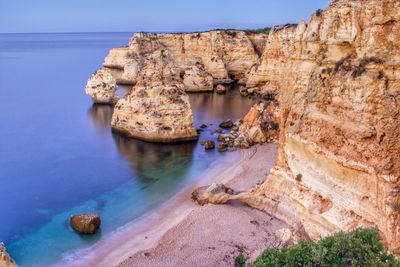 Scenic view of rock formations by sea at praia da marinha