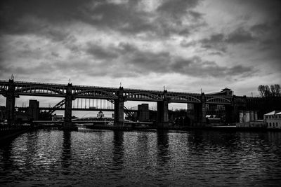 Bridge over river against cloudy sky